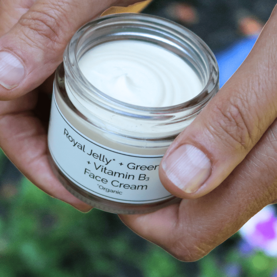 Hand holding a jar of face cream with a natural background